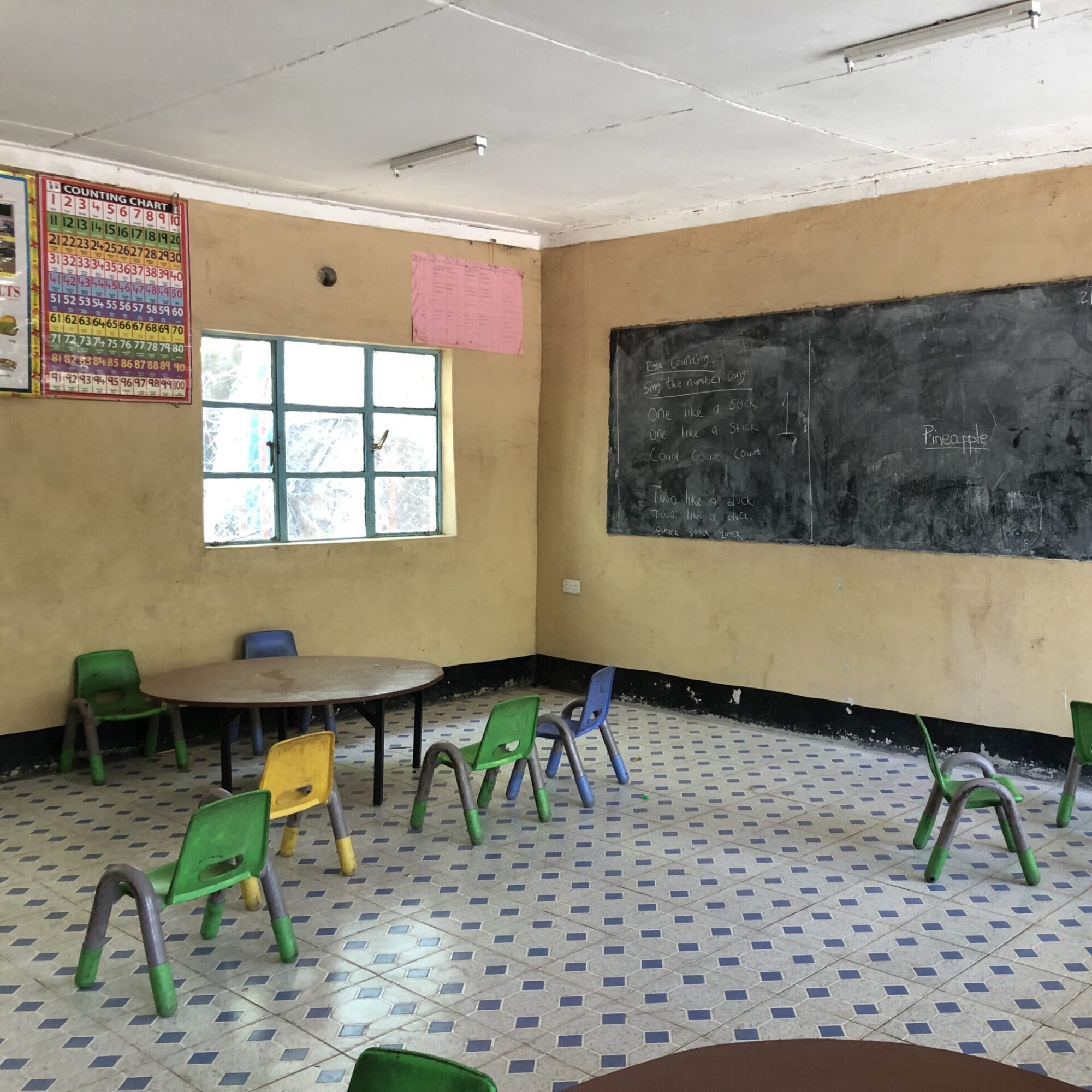 An empty classroom with small chairs and a window to the right of the room. Save JRS programs worldwide